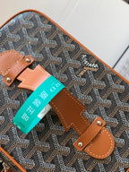 Small crossbody bag detail: tan handle strap, brown leather patch, teal tag attached.