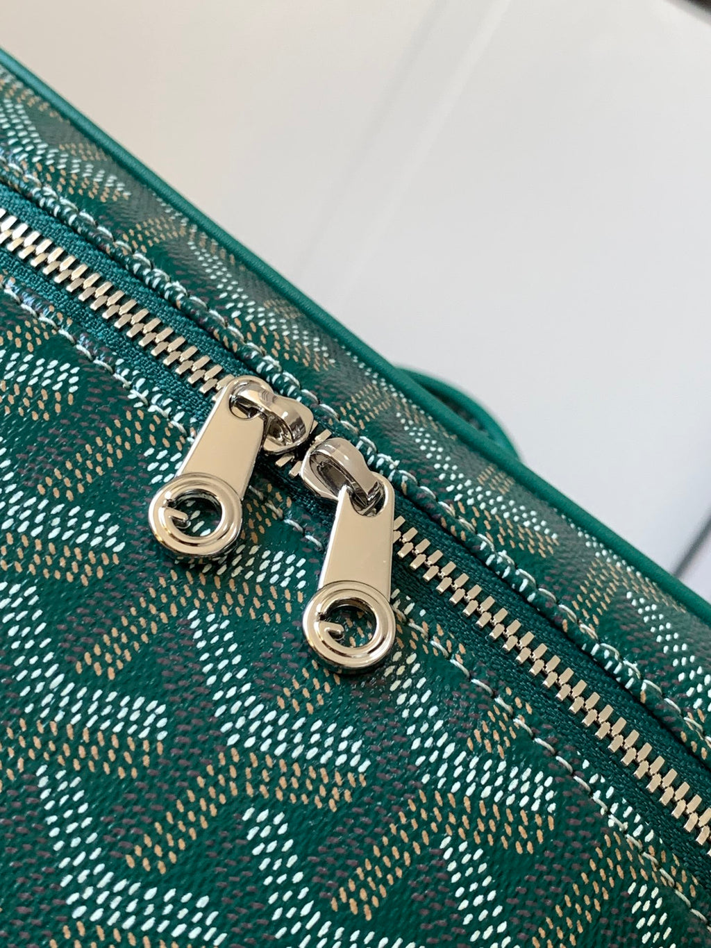 Goyard bag close-up: teal patterned fabric with gold-tone zipper hardware and rings