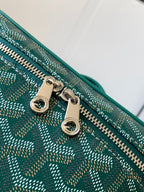 Goyard bag close-up: teal patterned fabric with gold-tone zipper hardware and rings