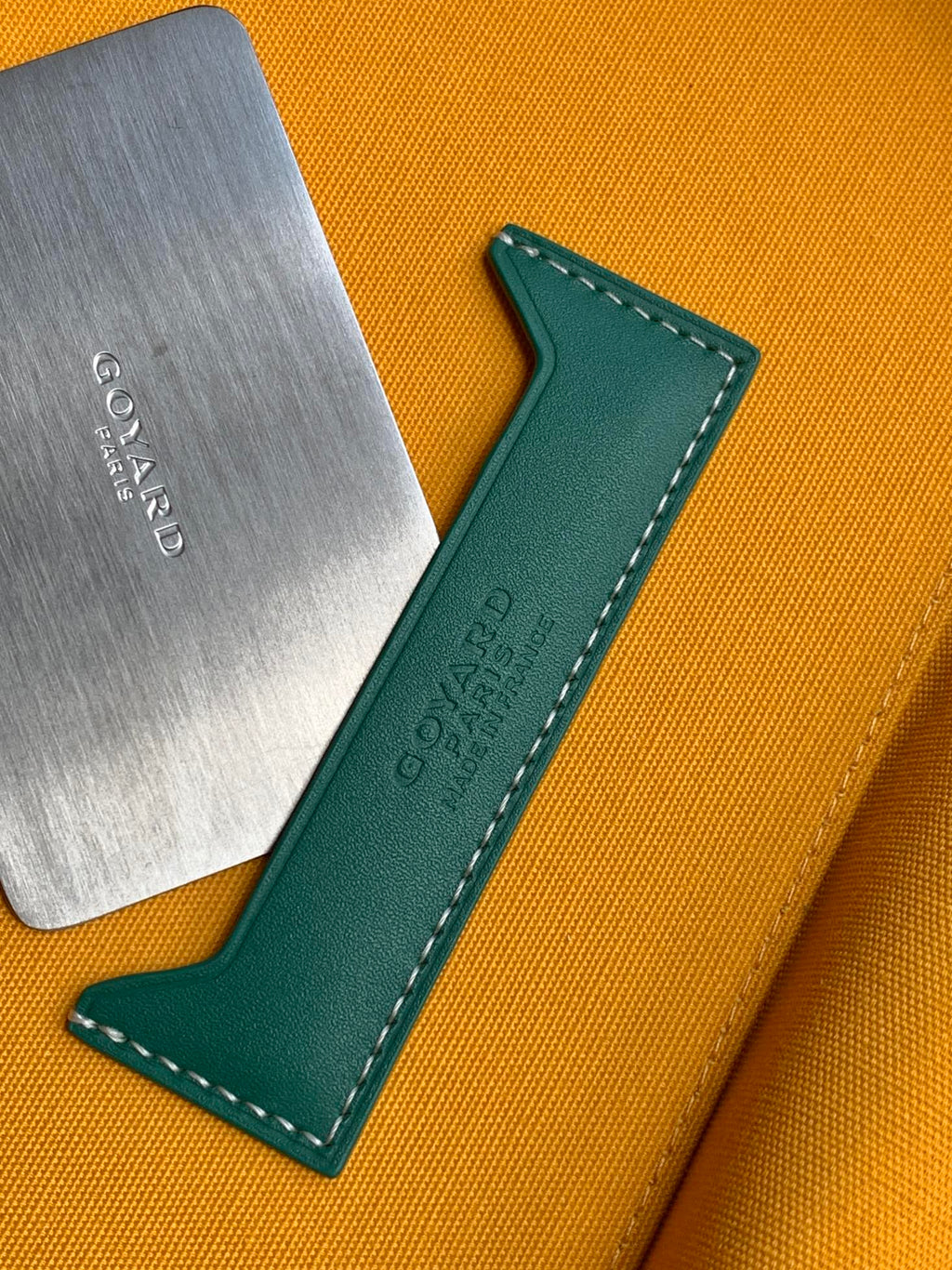 Small bag detail: metal brand plate and green leather label on yellow lining