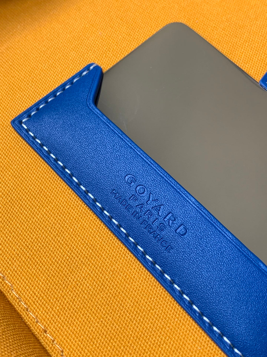 Blue leather strap patch with stamped lettering on an orange bag panel