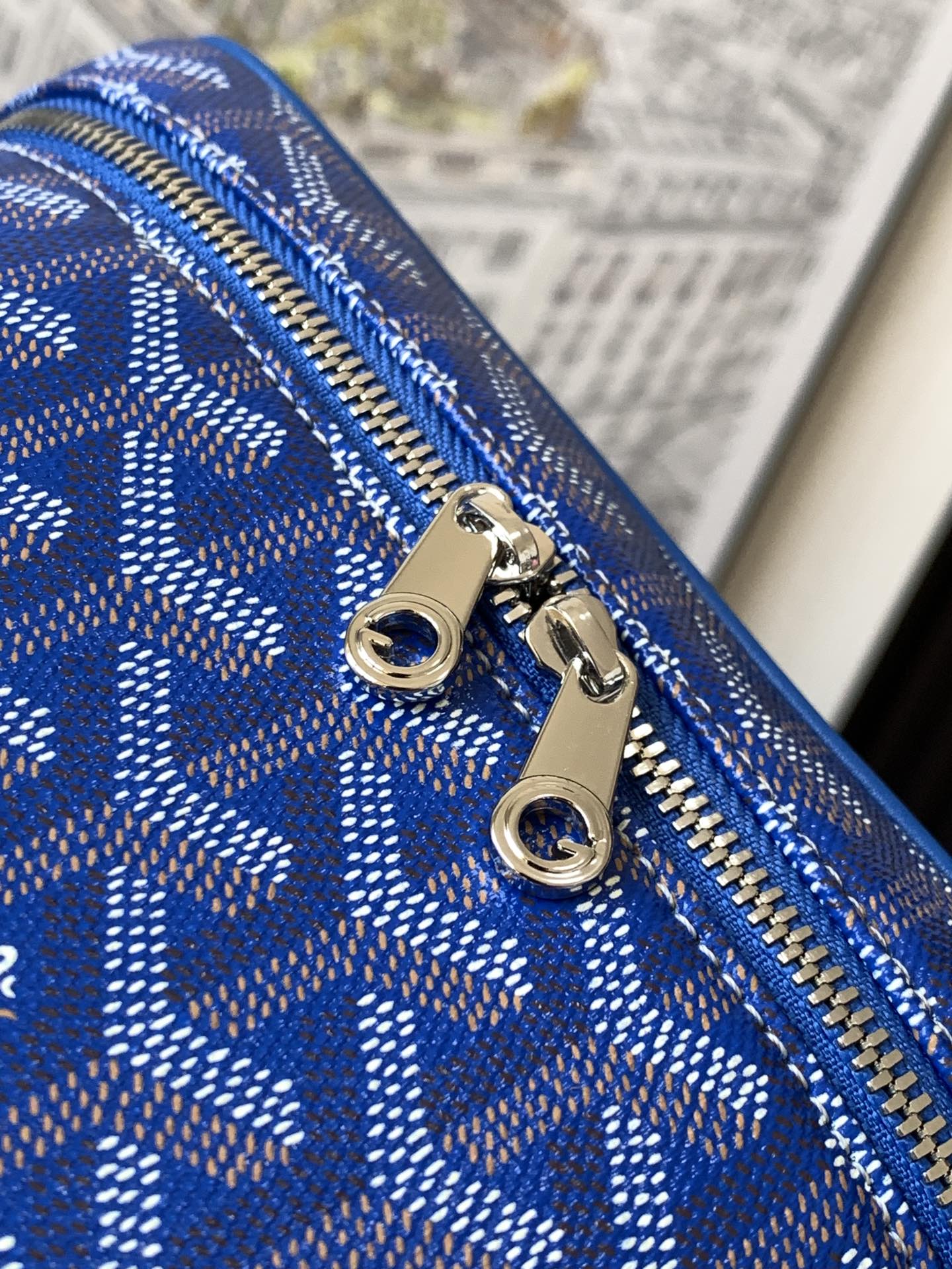 Blue patterned zipper close-up with silver pull tabs and rings