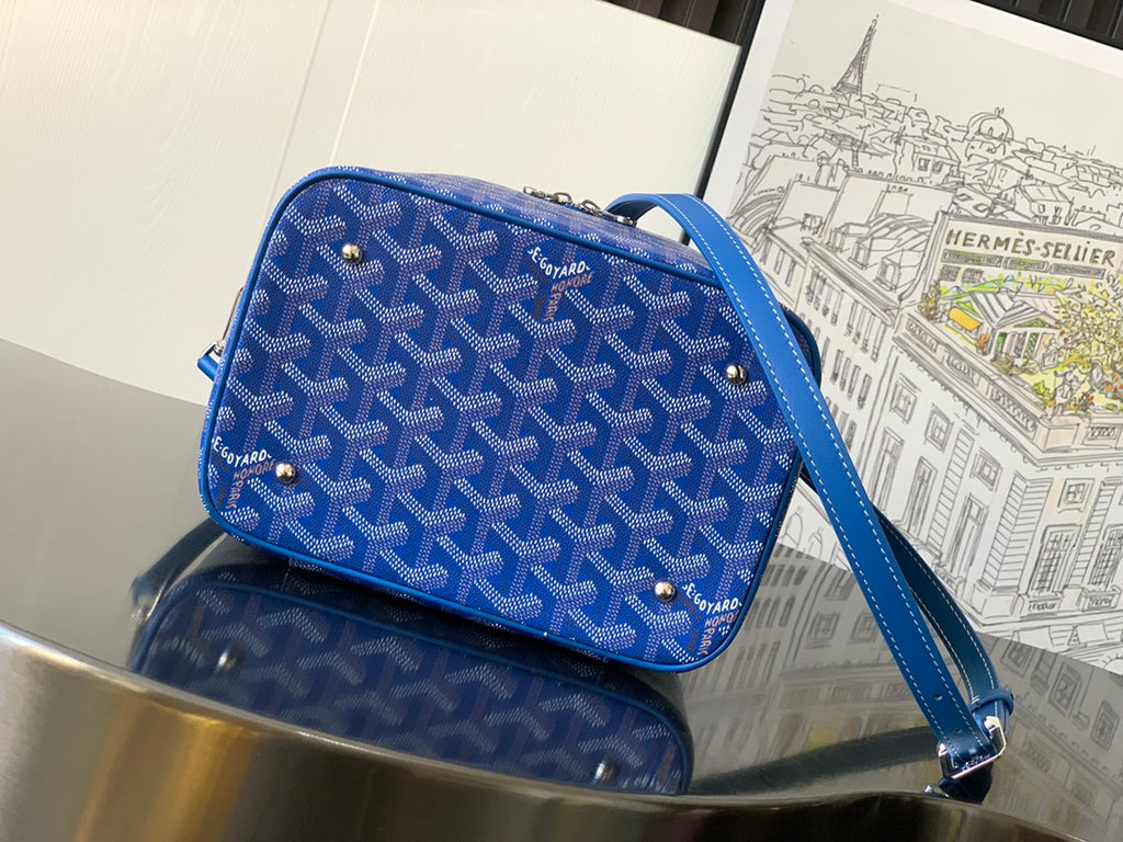 Blue patterned small bag with crossbody strap, zip top, and metal feet