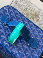 Blue patterned small bag with handle strap and metal studs, turquoise tag