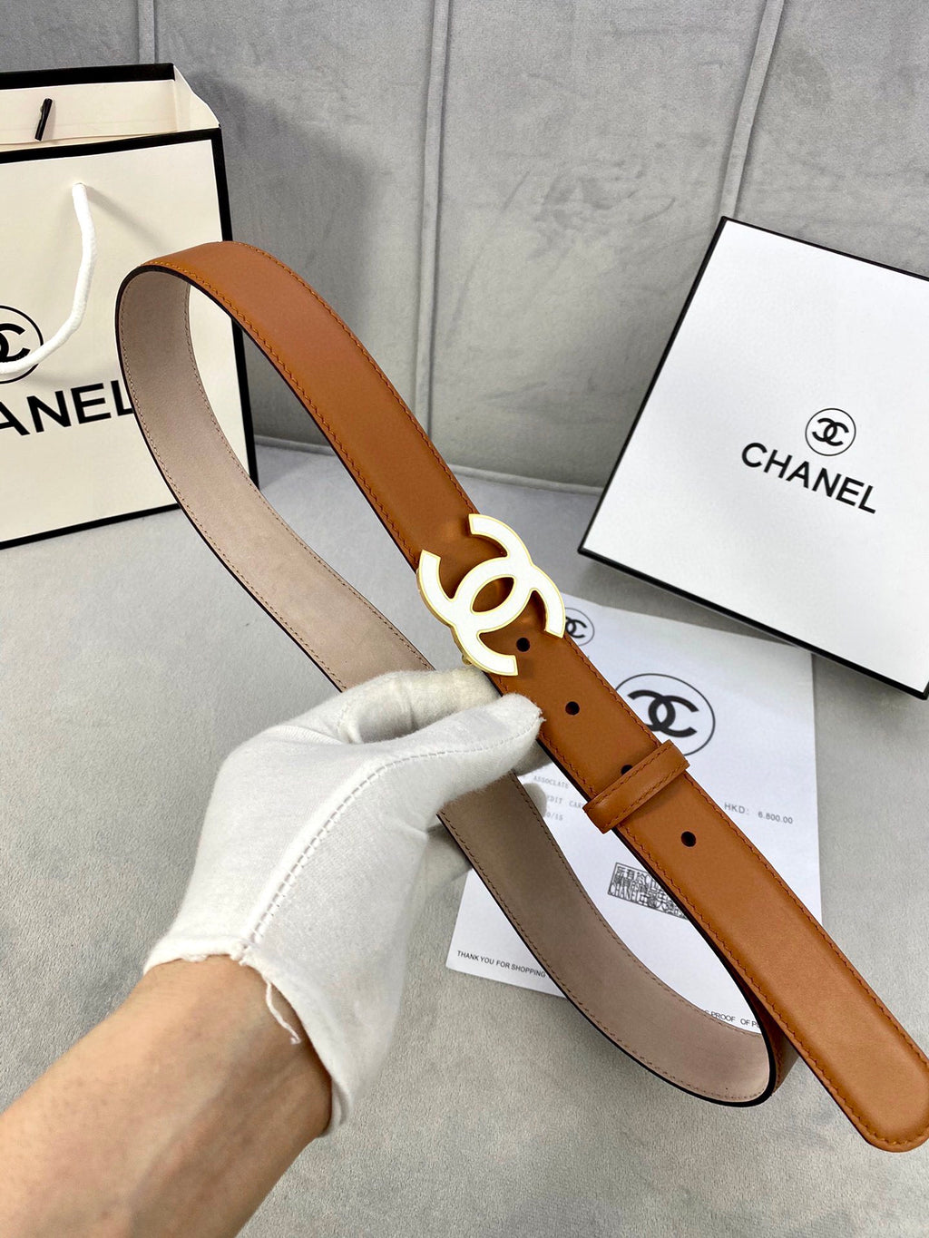 Chanel belt on hand, tan leather strap with gold-tone CC buckle and endkeeper