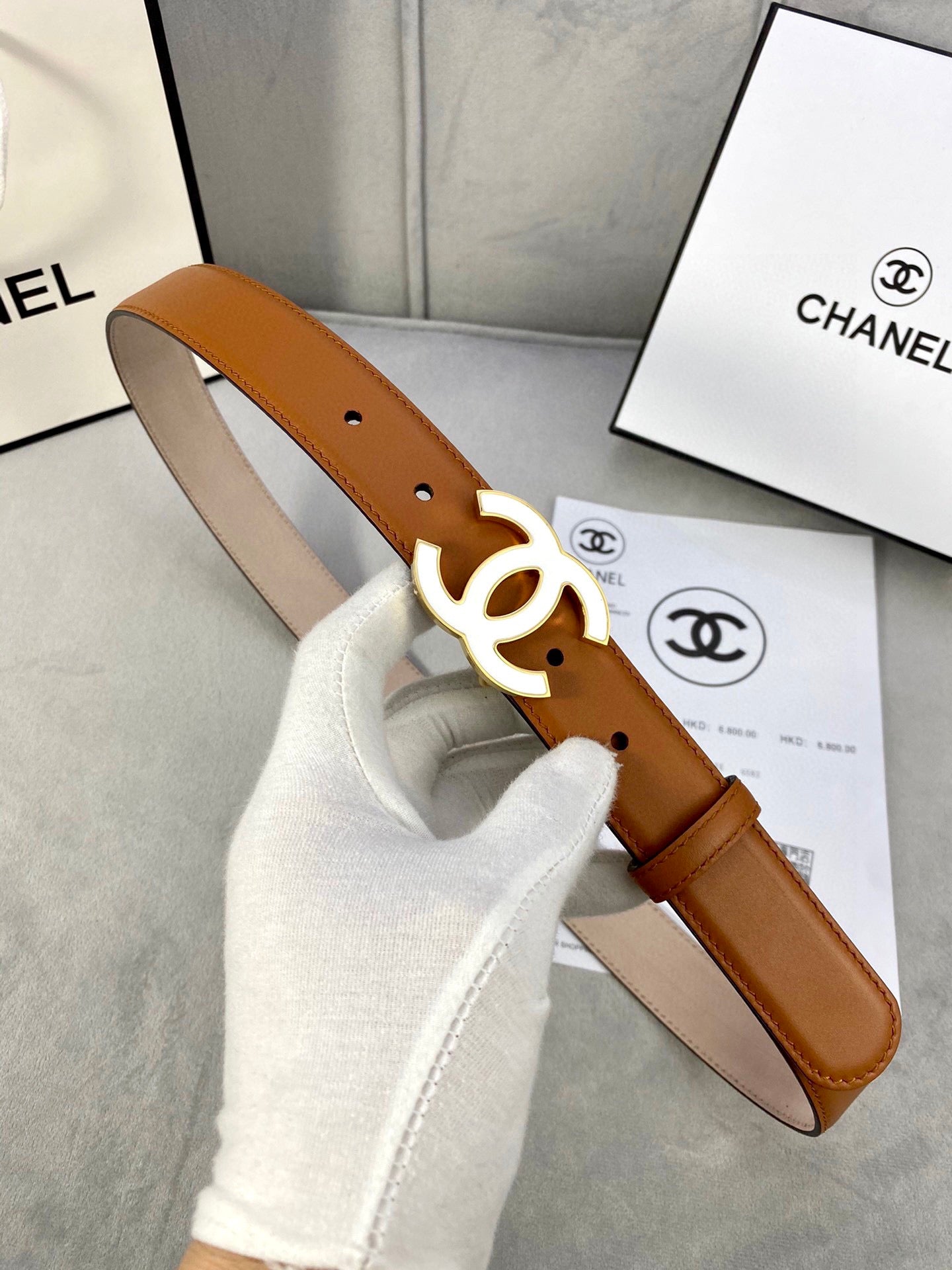 Chanel belt held up, tan leather with gold-tone CC logo buckle and strap holes