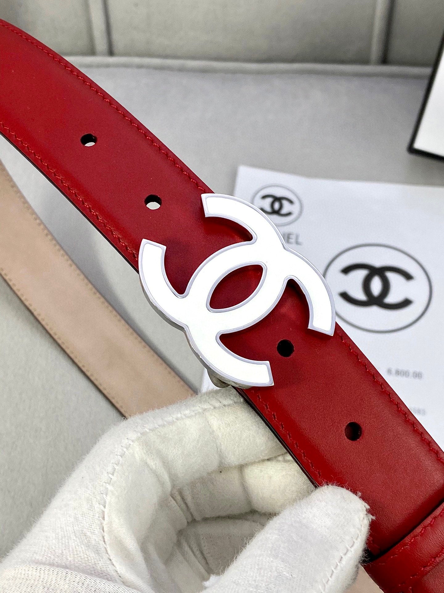 Close-up of red leather belt with gold-tone CC logo buckle and eyelet holes