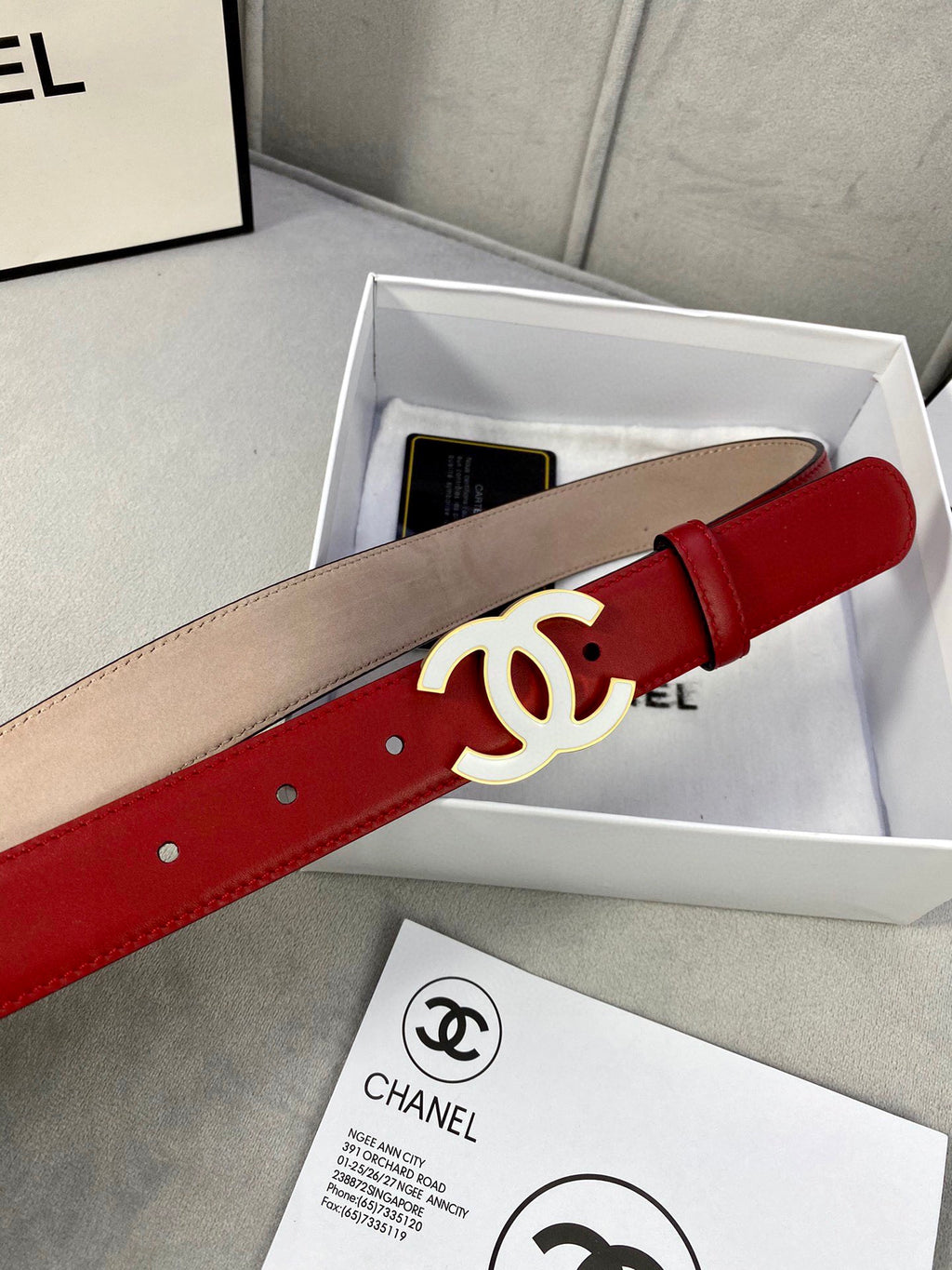 Red and beige leather belt with gold-tone CC buckle in storage box