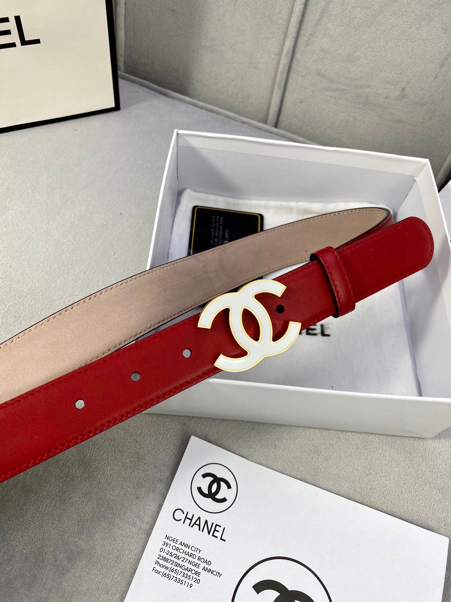 Red and beige leather belt with gold-tone CC buckle in storage box