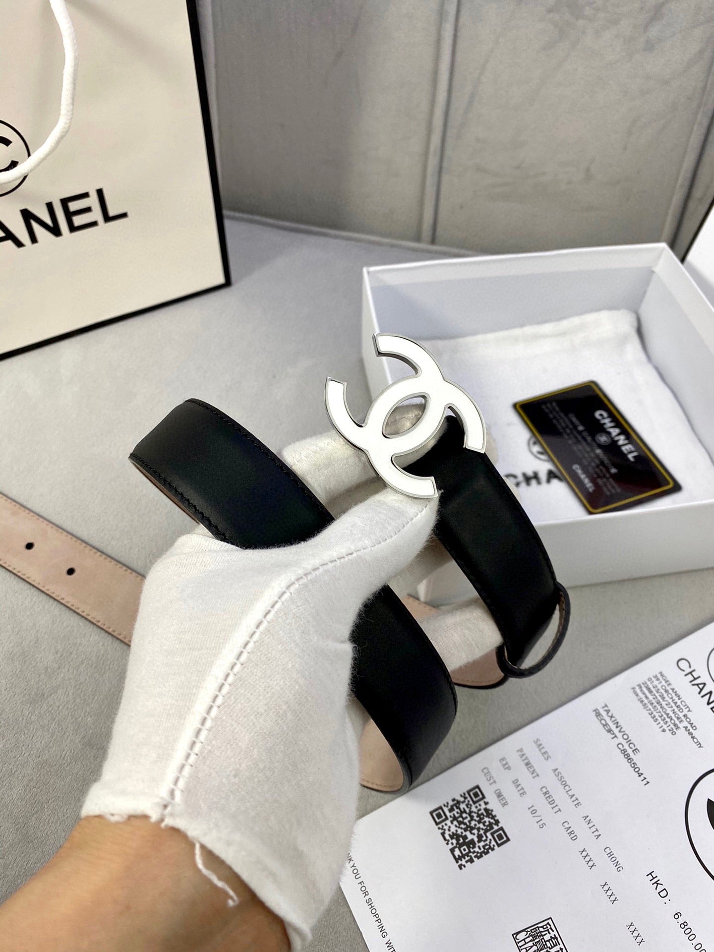 Black leather belt with gold CC buckle, shown above documents in a box