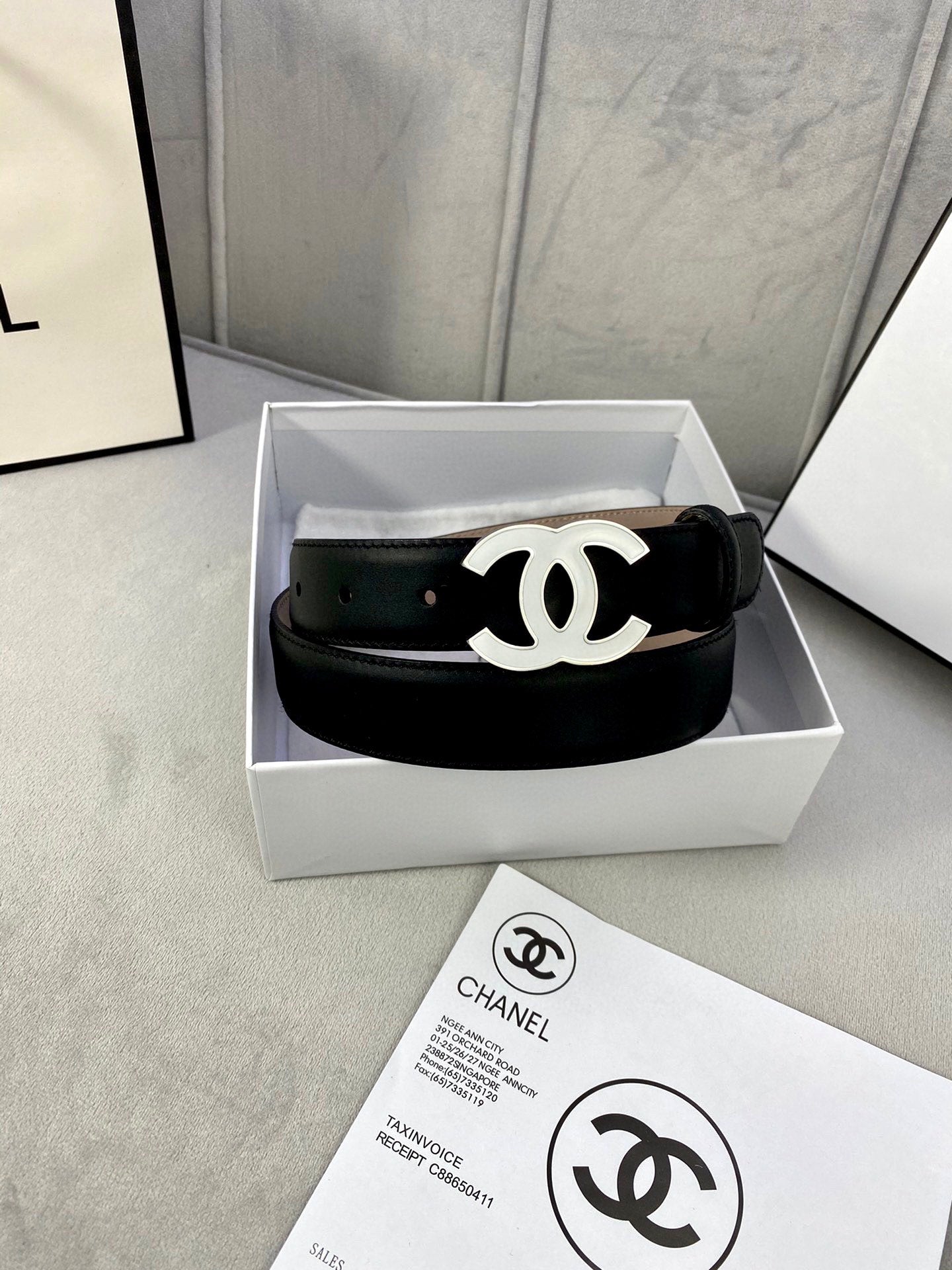 Black leather belt with gold CC buckle, neatly placed in a white gift box