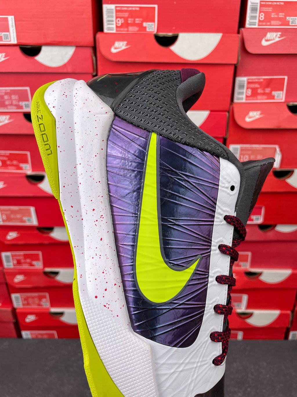 Low-top basketball shoe with dark mesh toe, purple heel panel, neon green accents