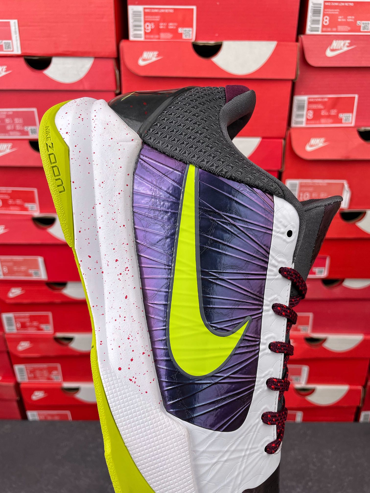 Low-top basketball shoe with dark mesh toe, purple heel panel, neon green accents