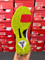 Low-top basketball shoe outsole view: neon yellow-green tread with purple emblem