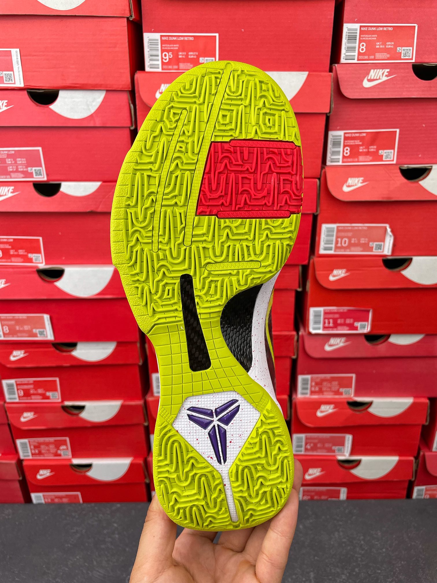 Low-top basketball shoe outsole view: neon yellow-green tread with purple emblem