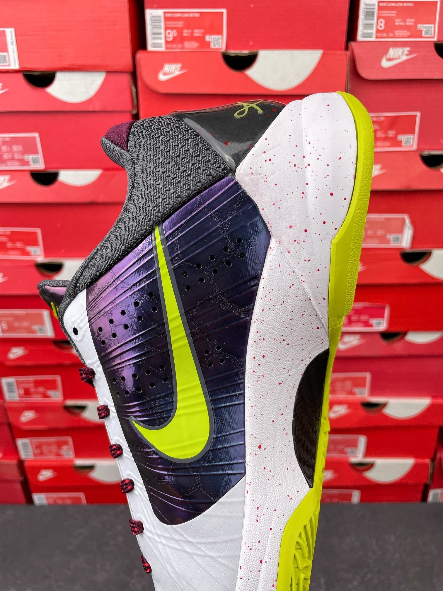 Low-top basketball shoe outsole side: neon yellow-green sole with white and purple upper