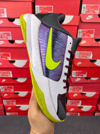 Low-top basketball shoe side view with white, purple, and neon green detailing