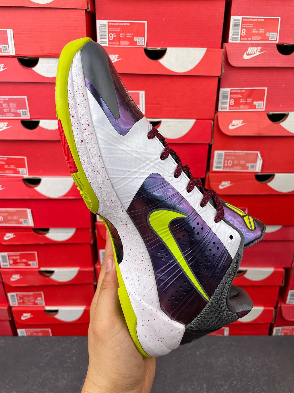 Low-top basketball shoe angled side view: white and purple upper with dark laces
