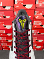 Low-top basketball shoe heel view: black collar, white sides, red laces, neon detail