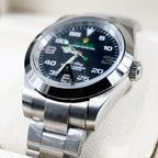 Rolex watch with black dial, green hands, and stainless steel bracelet