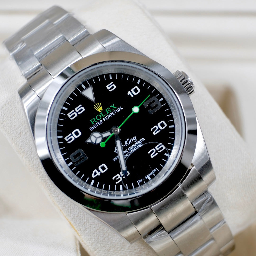 Rolex watch angled view with black dial, green accents, steel bracelet