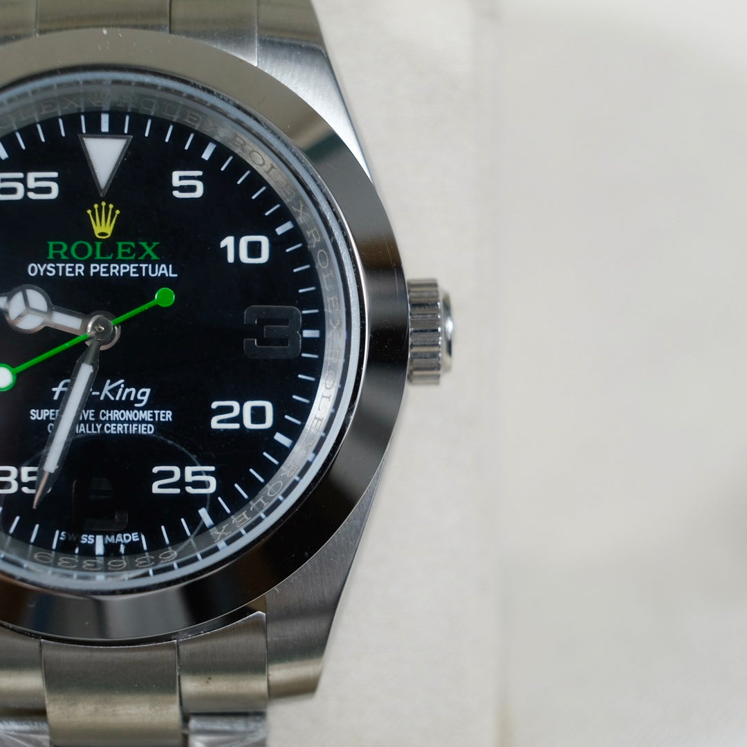 Rolex watch dial close-up with black face, green hands, steel case