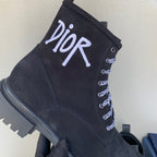 Black suede ankle boot with large white Dior logo and patterned lace eyelets