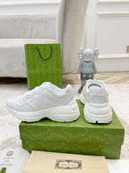 White Gucci lace-up sneaker set with heel and side visible on green box