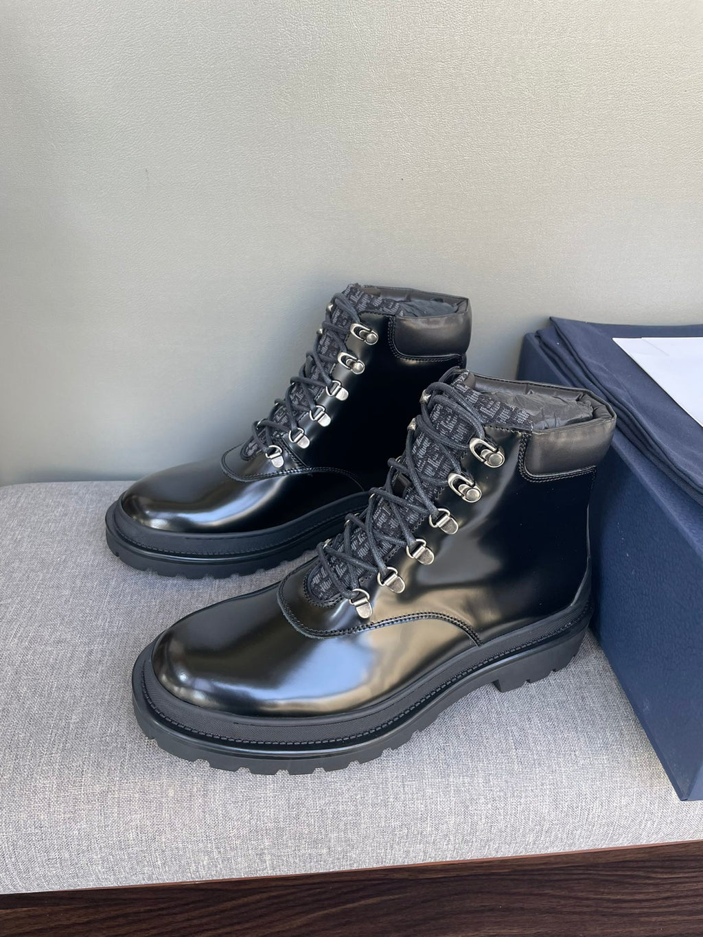 Black lace-up ankle boots with metal rings and padded collar, on stand