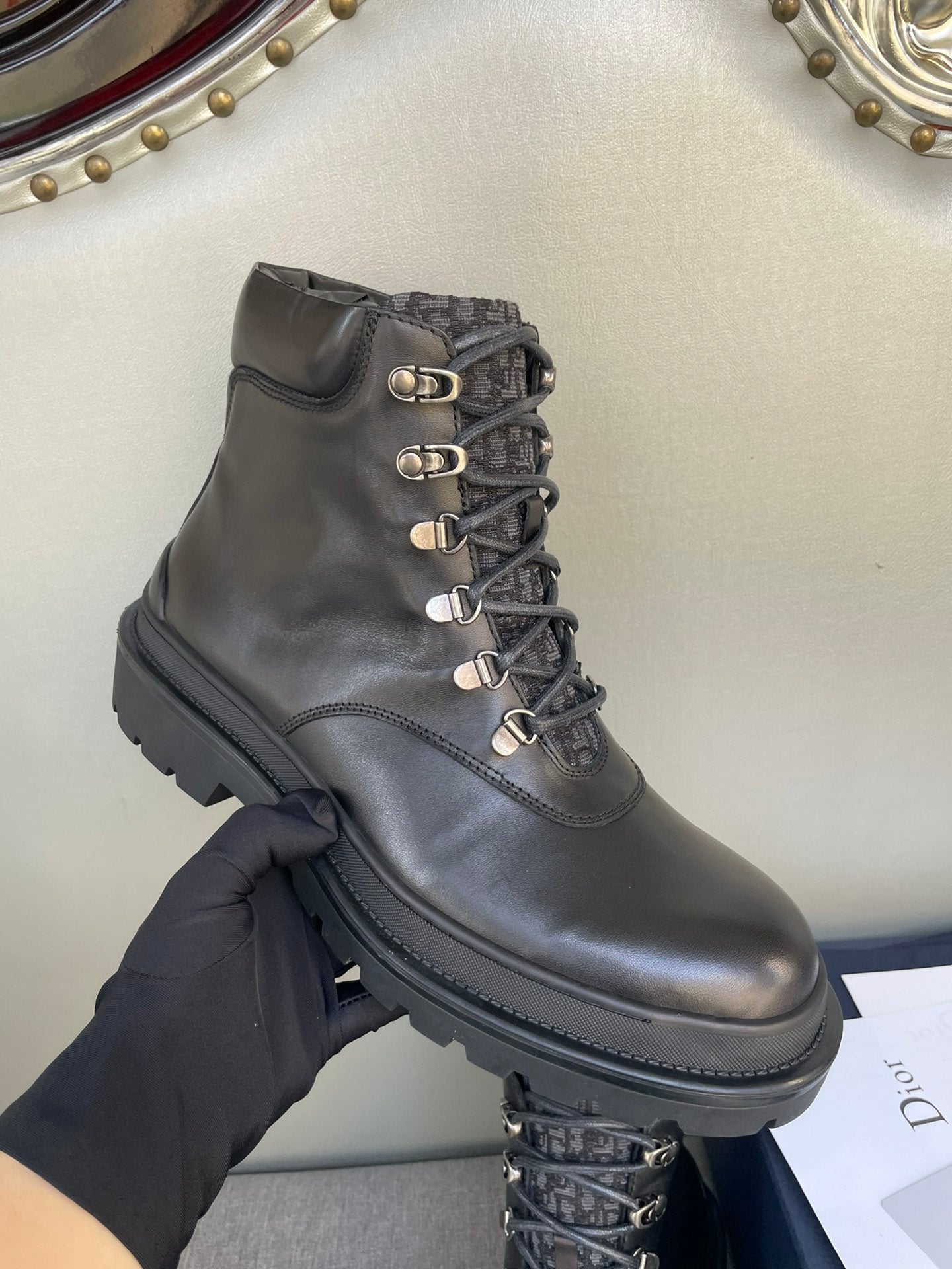 Dark leather lace-up boot with gold D-ring eyelets, rounded toe, thick sole