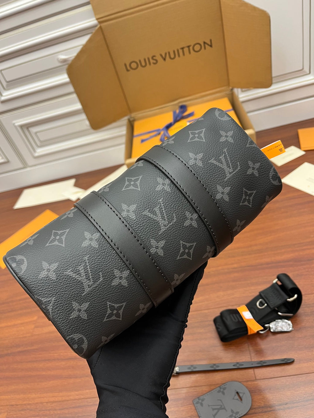 Men's Louis Vuitton monogram bag laid flat, dark gray with stitched trim