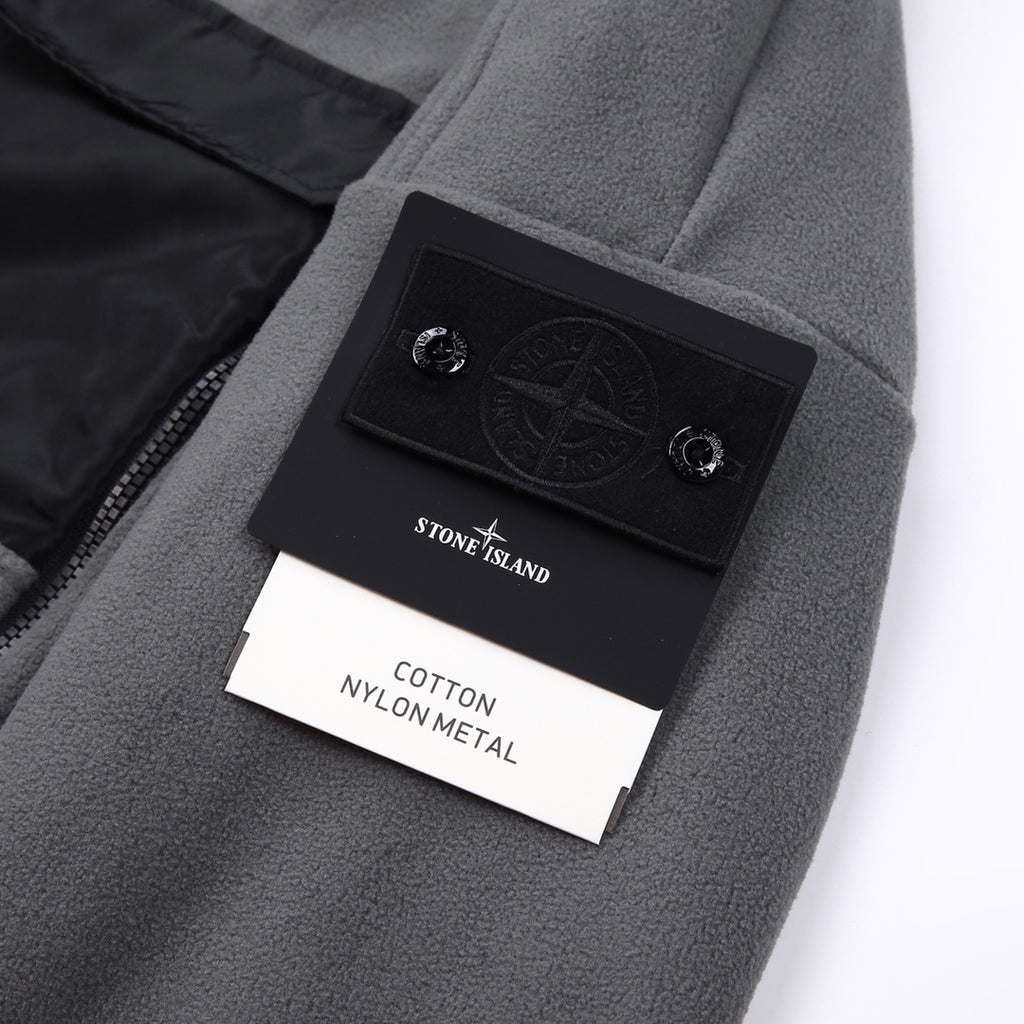 Stone Island jacket label area, gray fleece with black logo patch and tag
