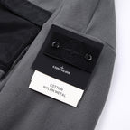 Stone Island jacket label area, gray fleece with black logo patch and tag