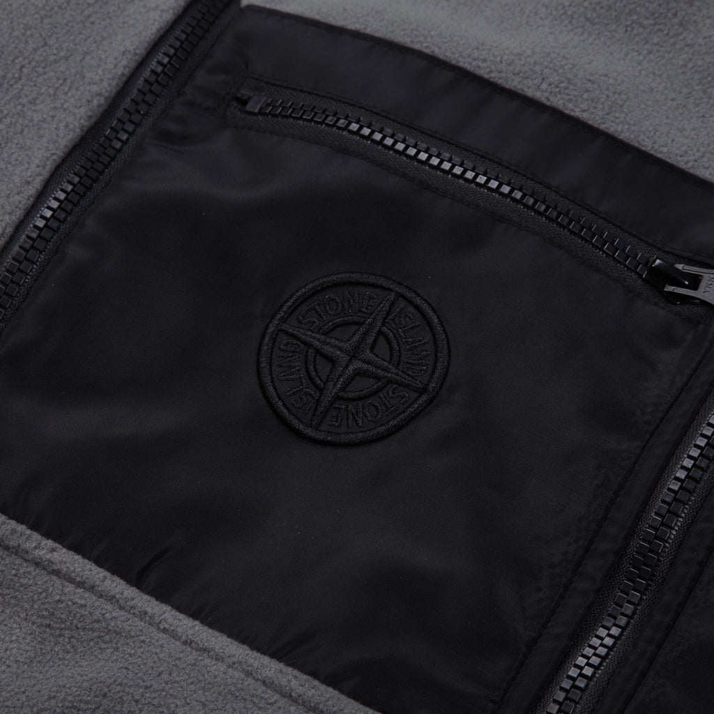 Stone Island logo patch on black lining, framed by zippered pocket opening