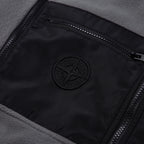 Stone Island logo patch on black lining, framed by zippered pocket opening