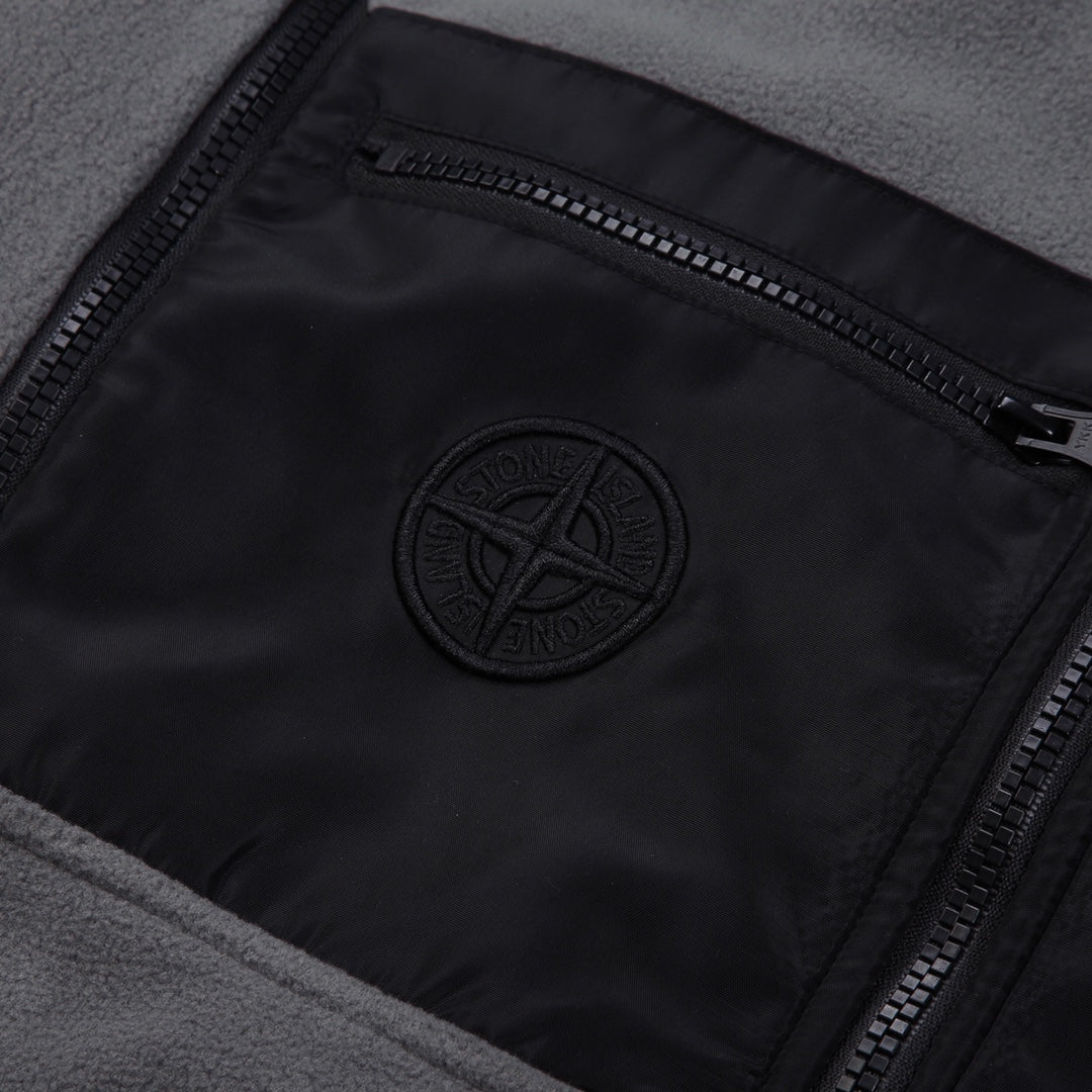 Stone Island logo patch on black lining, framed by zippered pocket opening