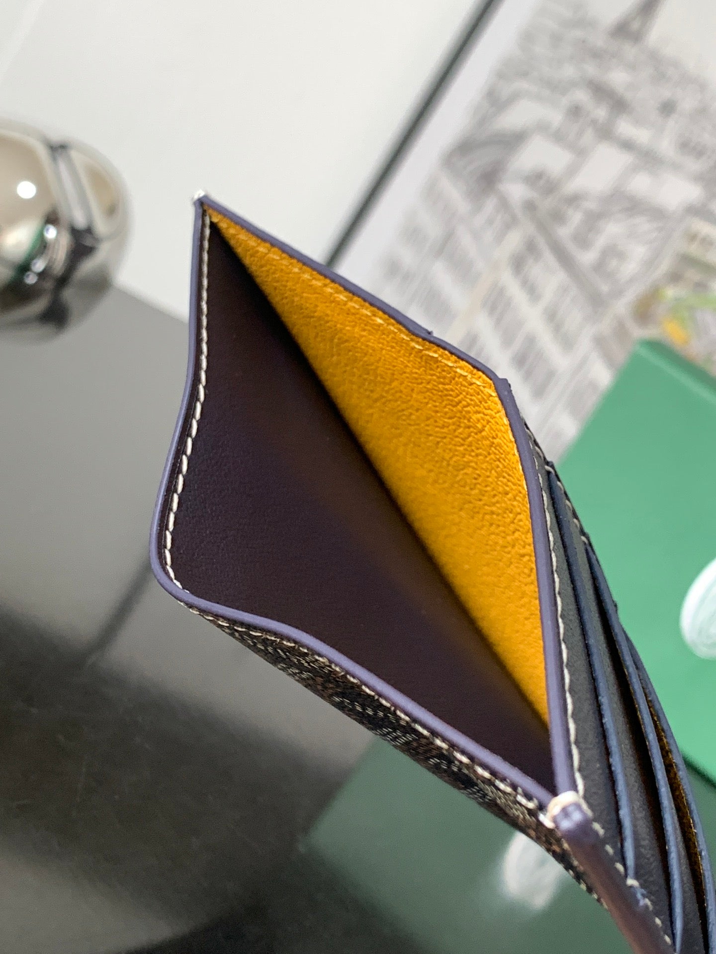 Small cardholder bag with open fold showing dark navy exterior and yellow interior