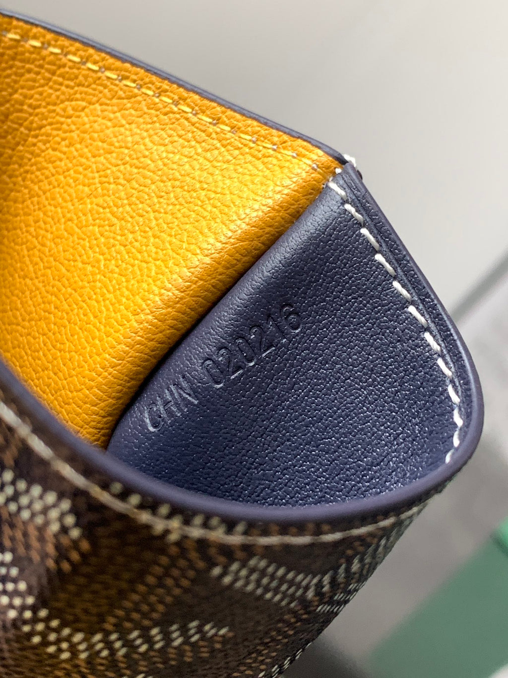 Small cardholder bag open with yellow lining and embossed navy exterior