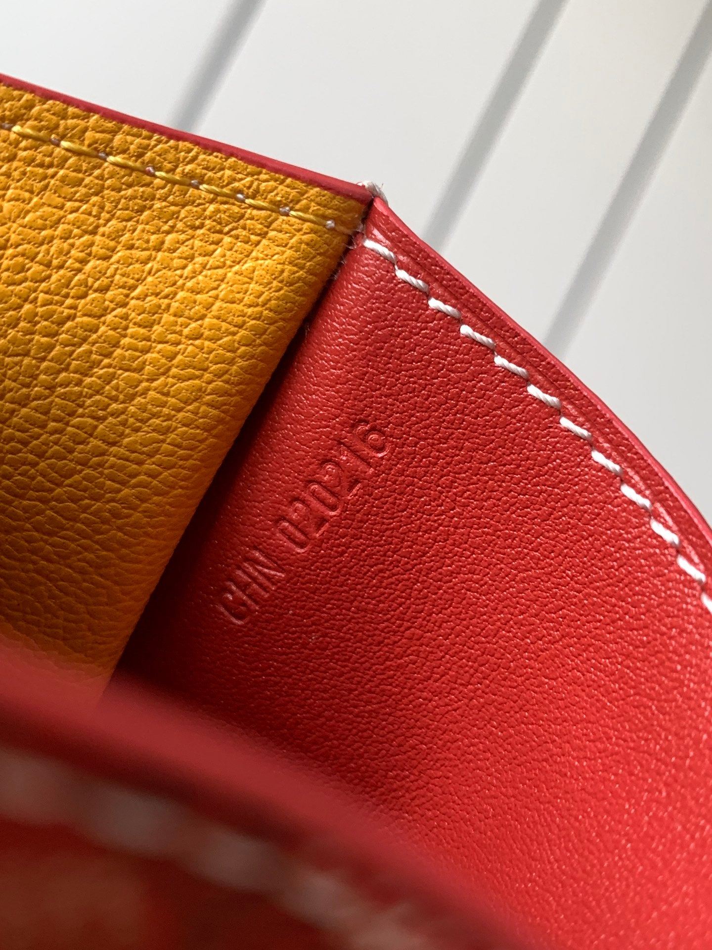 Goyard wallet edge close-up with red leather, yellow lining, and contrast stitching