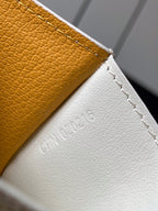 Small bag edge with embossed text on white leather, yellow trim and stitched seam