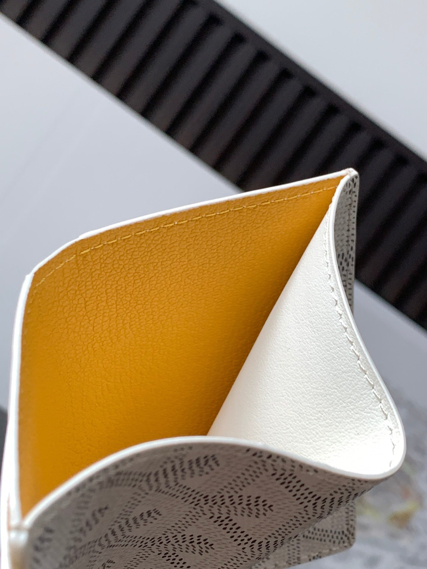 Small bag with yellow interior lining and white exterior, curved flap detail