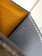 Small bag close-up on dark gray pebbled leather with white stitching and embossed logo.