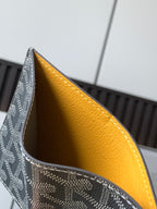 Small bag open to show honey-yellow interior lining and dark gray monogram exterior.