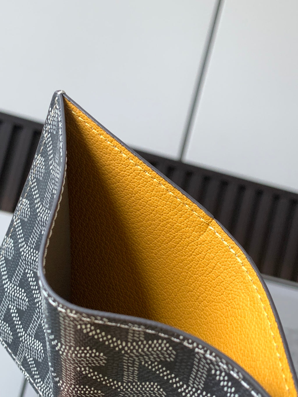 Goyard small wallet with gray exterior and mustard yellow interior lining.