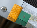 Orange patterned Goyard bag with green panel and snap closure