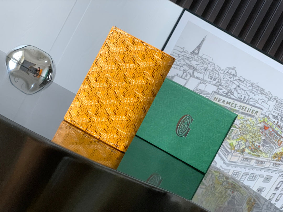Orange patterned Goyard bag with green panel and snap closure