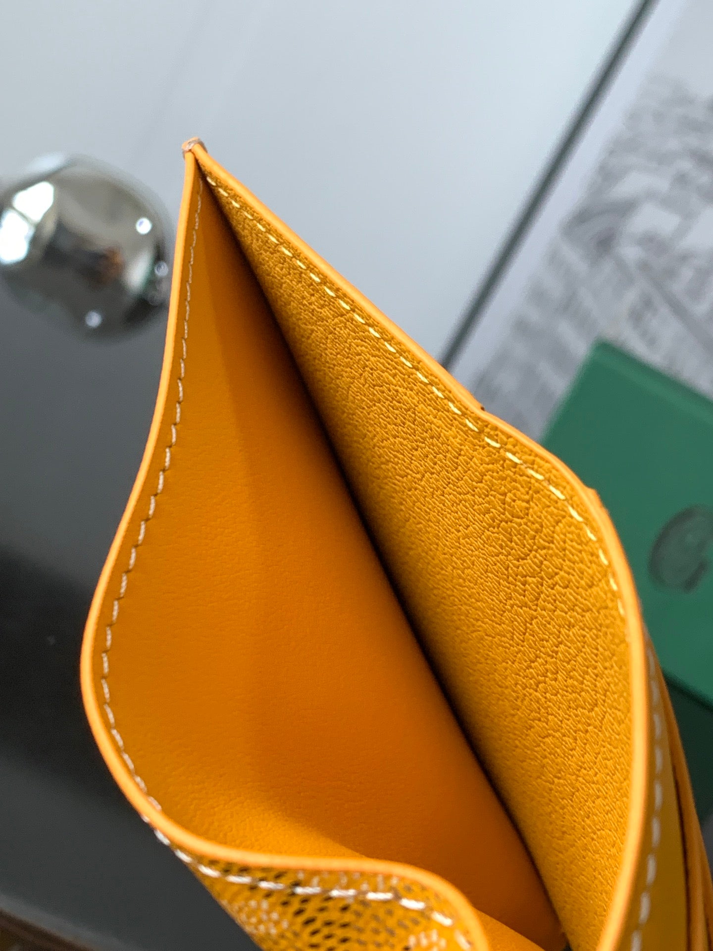 Yellow leather small bag opening edge with white stitching, close-up