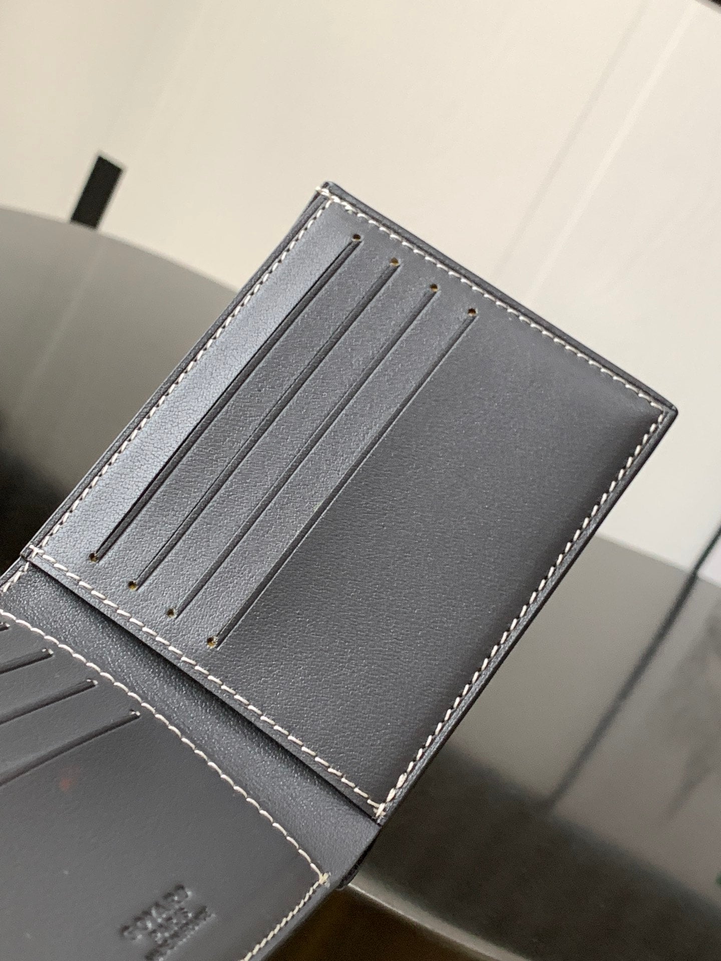Small leather bag with four thin metal rods and contrast white stitching at edges