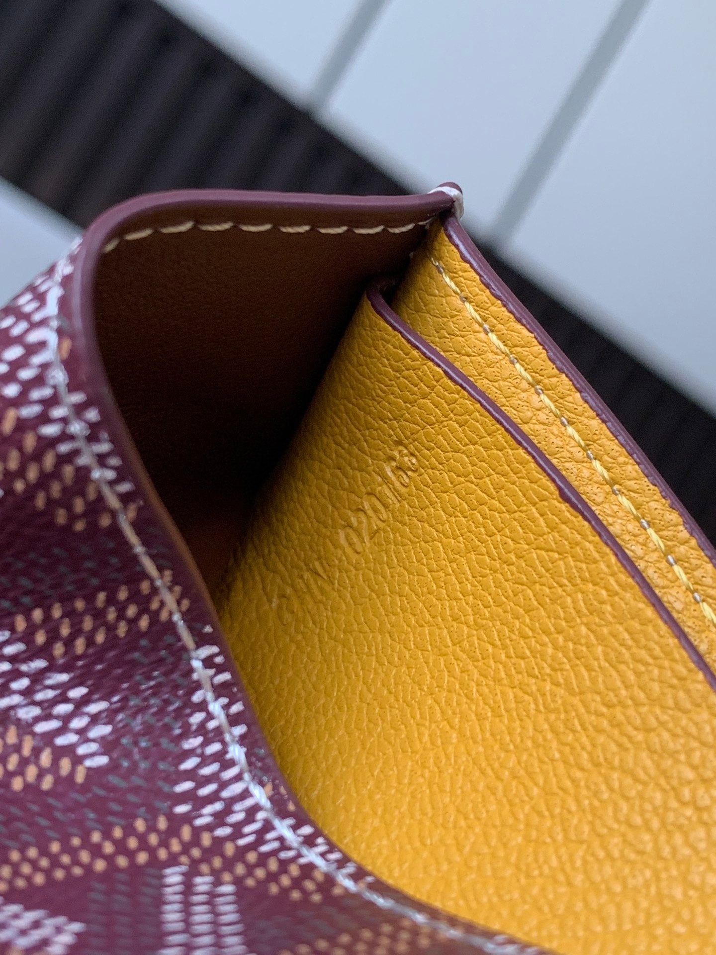 Small Goyard bag interior with mustard-yellow leather lining and burgundy inner edge.