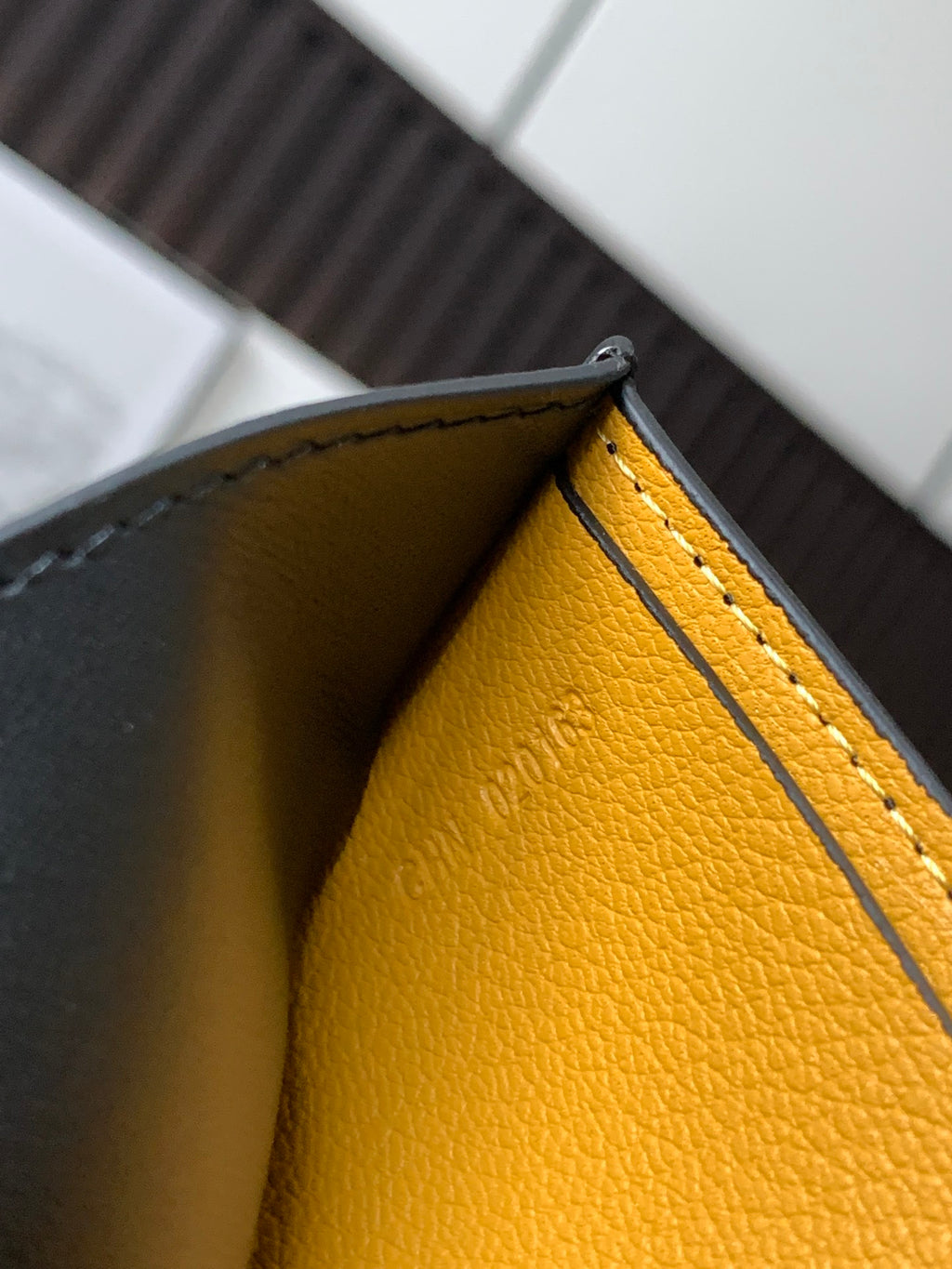 Leather wallet interior corner with yellow lining and stitched piping